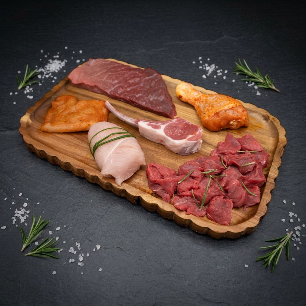 Inhoud Familie Bulk Mix Box: biefstuk, kipfilet, kip blindevink, lamskotelet, drumstick en runds blokjes op houten plank